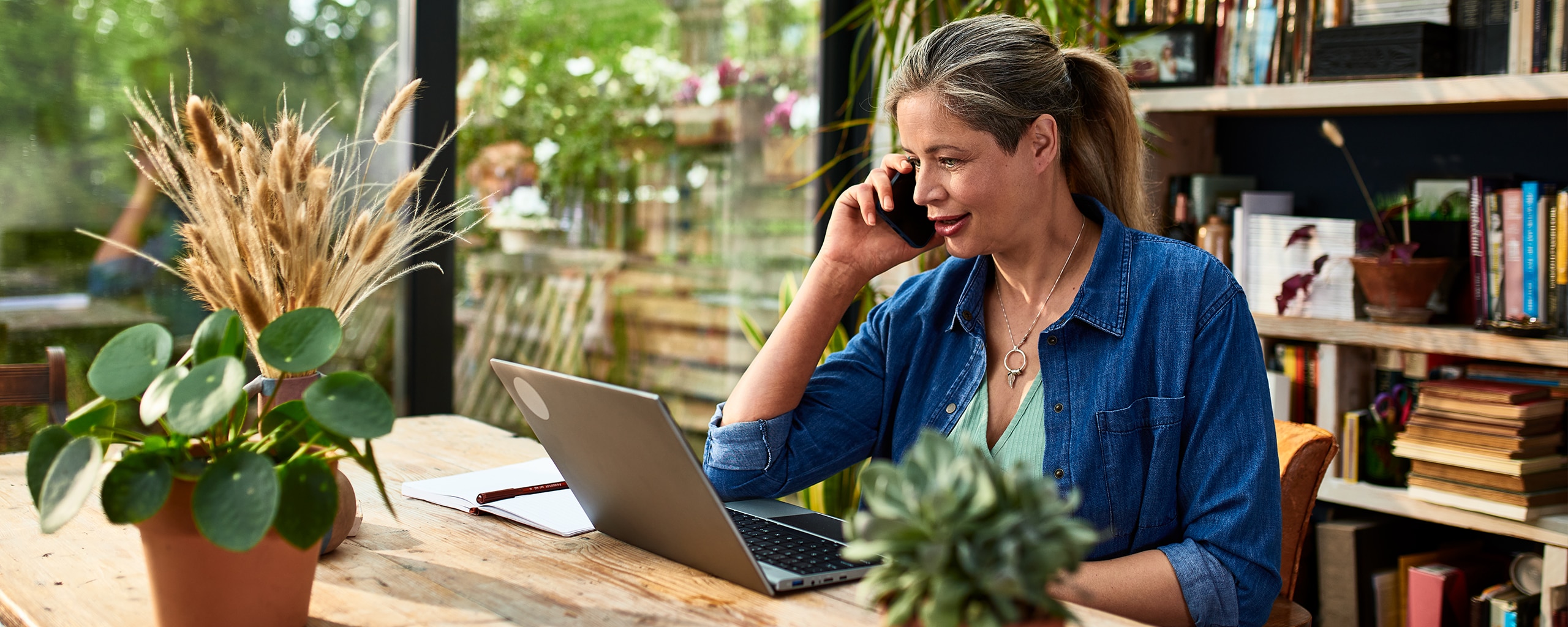 A person sits at her laptop and talks on a cellphone about how to protect herself from identity theft.