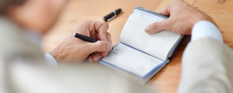 A person fills out a check with a pen.