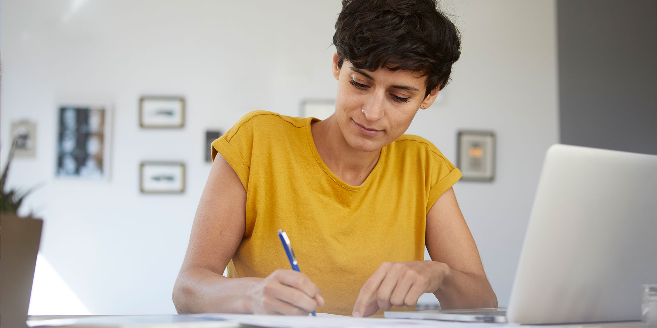 A person fills out a money order while sitting at their home desk.