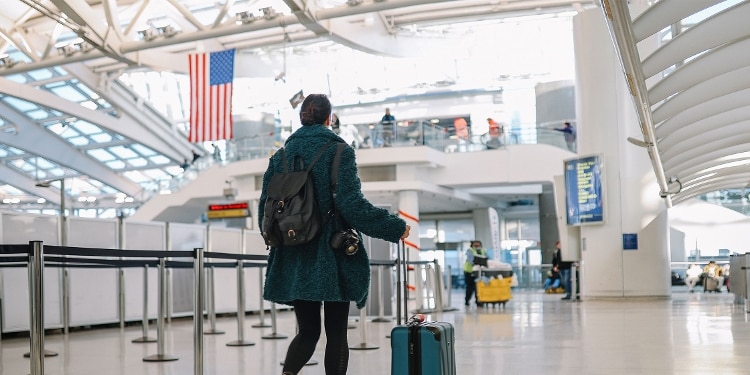 A photo of a person rolling their suitcase through a customs checkpoint in an airport.