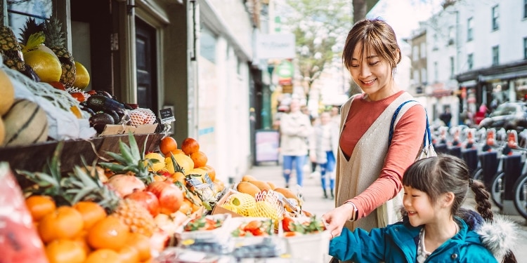 A parent and child shop at a fruit stand.