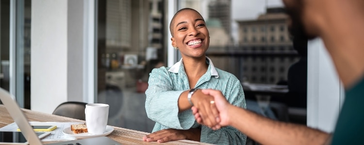 Company representative shaking hands and smiling with a client.