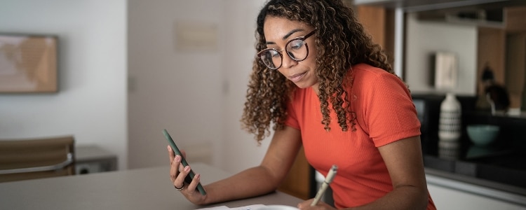 A woman uses her smartphone to check-in on her robo-advisor investment account.&nbsp;