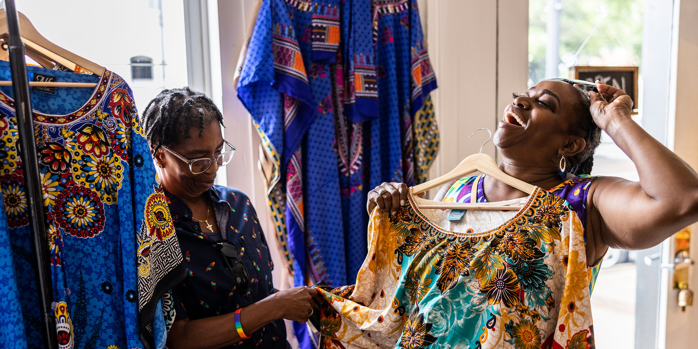 Two people smiling and shopping for clothes together.