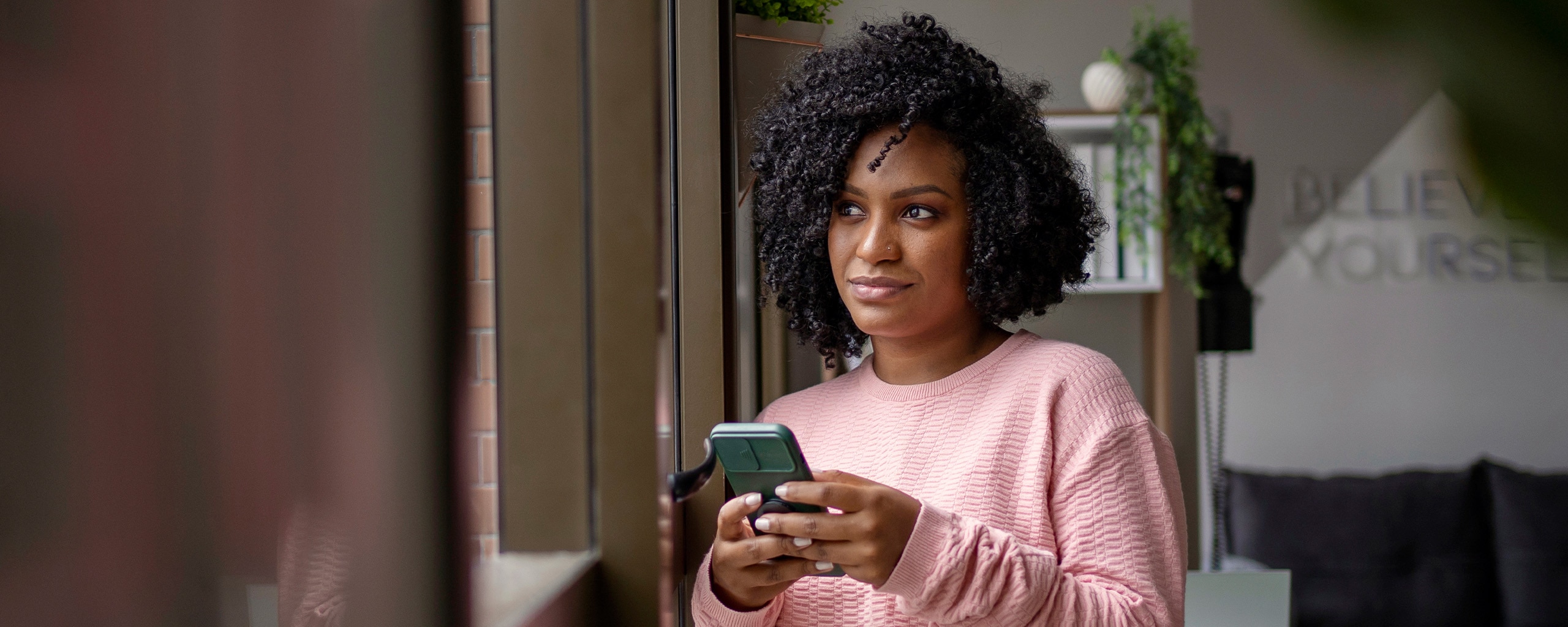 Young woman uses her phone to decide whether to use ACH or a wire transfer to send money.