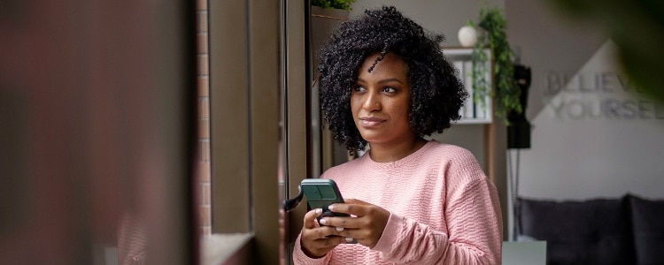 Young woman uses her phone to decide whether to use ACH or a wire transfer to send money.