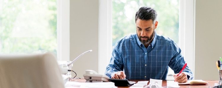 A person sits at a desk and calculates their equity.