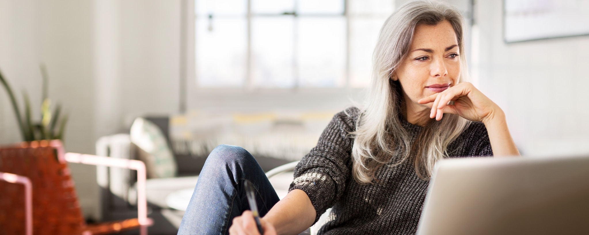 A person sitting down at a table writes something on a piece of paper.