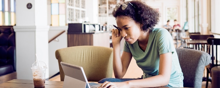 A college student sits in the library and reviews the terms of their subsidized loan.