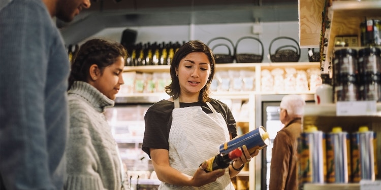 A couple listens to a grocery clerk explain food options.