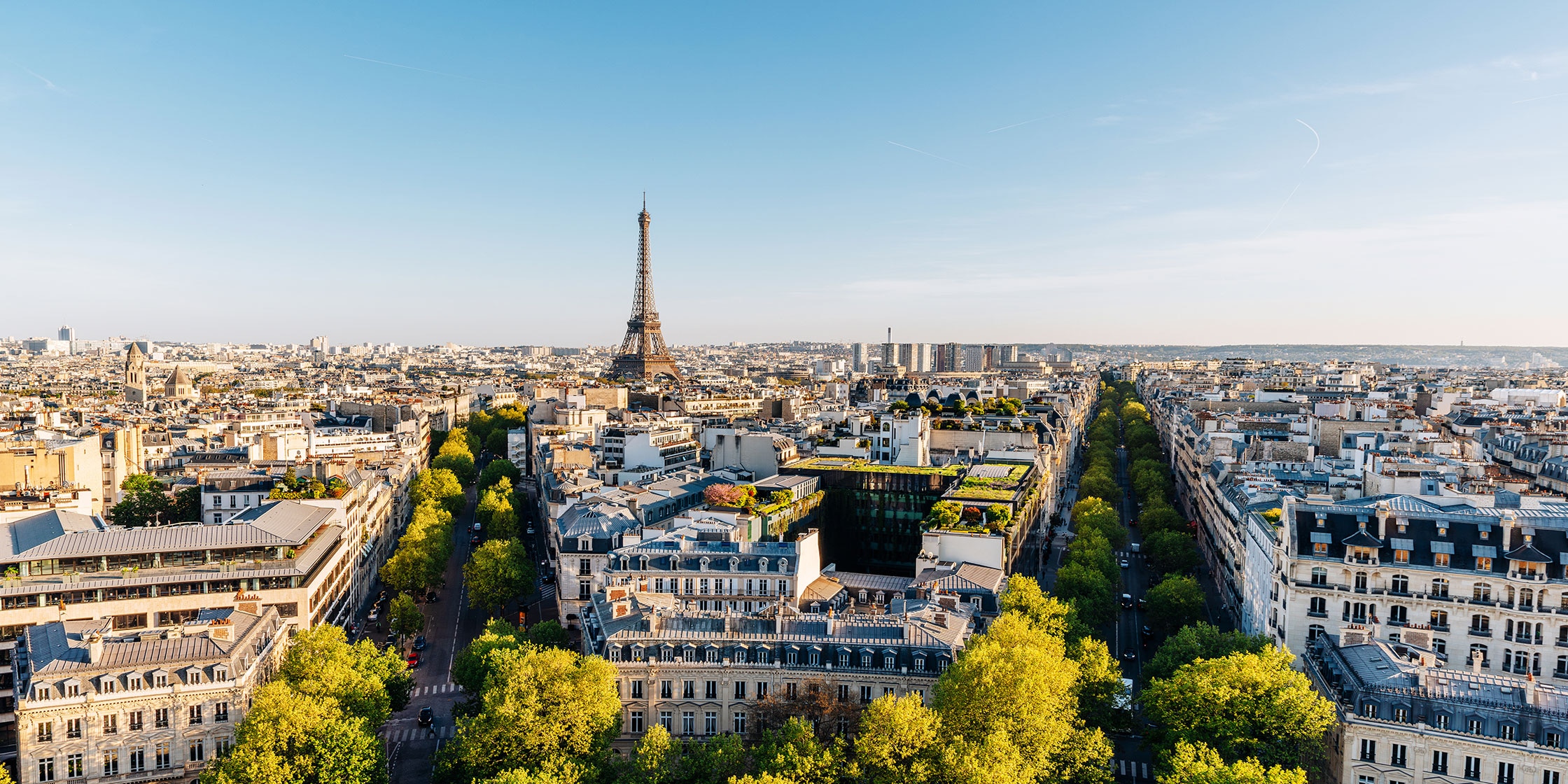 Aerial view of the rooftops of Paris, with the Eiffel Tower in the distance.