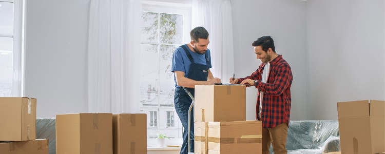 A person tips a mover amid cardboard packing boxes.