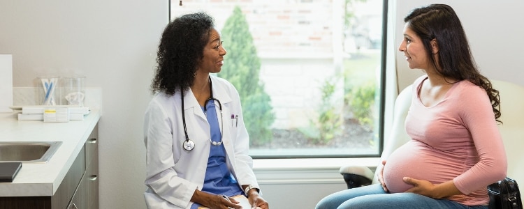 A pregnant woman talks to her doctor about medical expenses.