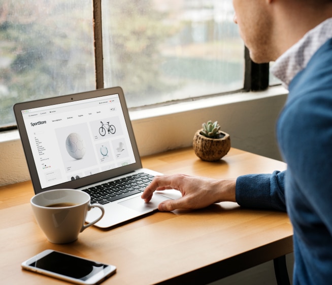 Person sitting at desk scrolling on their laptop.