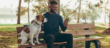 Man and his dog, on a bench in a park.