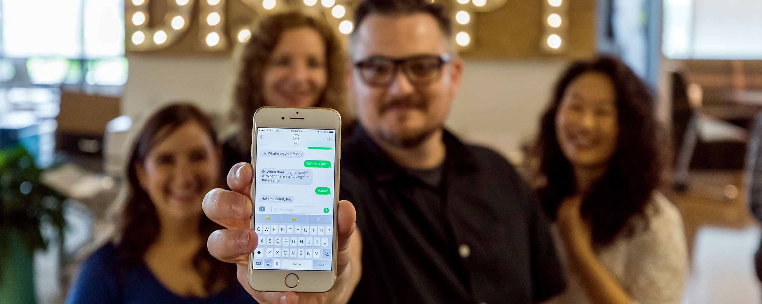 Person holding a smartphone showing a text conversation with Eno, Your Capital One assistant.