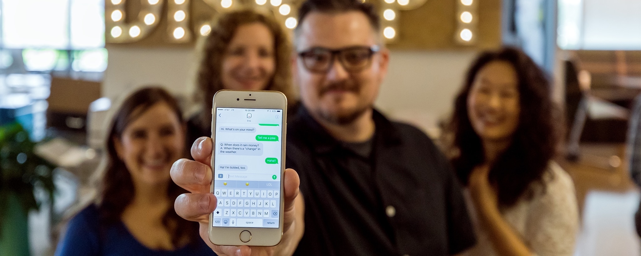 Person holding a smartphone showing a text conversation with Eno, Your Capital One assistant.
