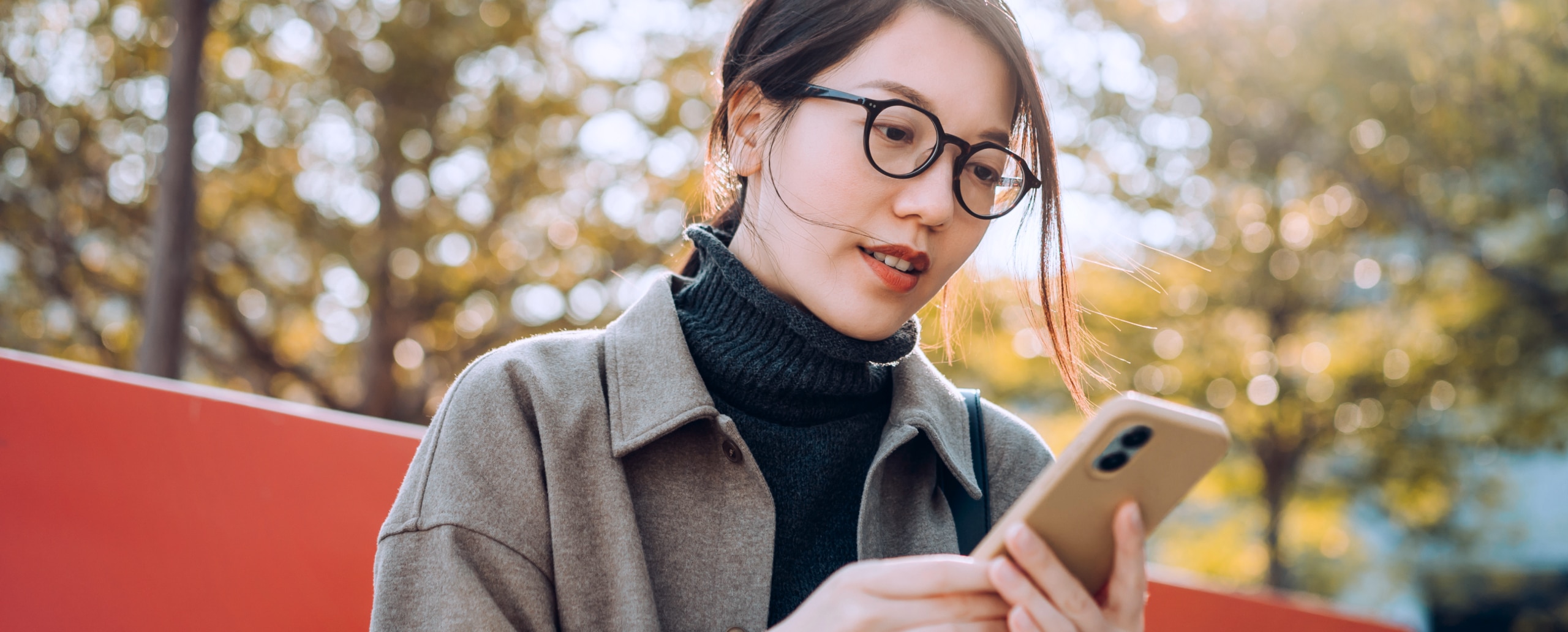 Young woman sitting outside and looking at her smartphone