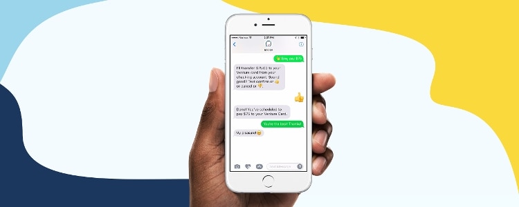 Hand holding a smartphone showing messages from Eno, Your Capital One assistant.