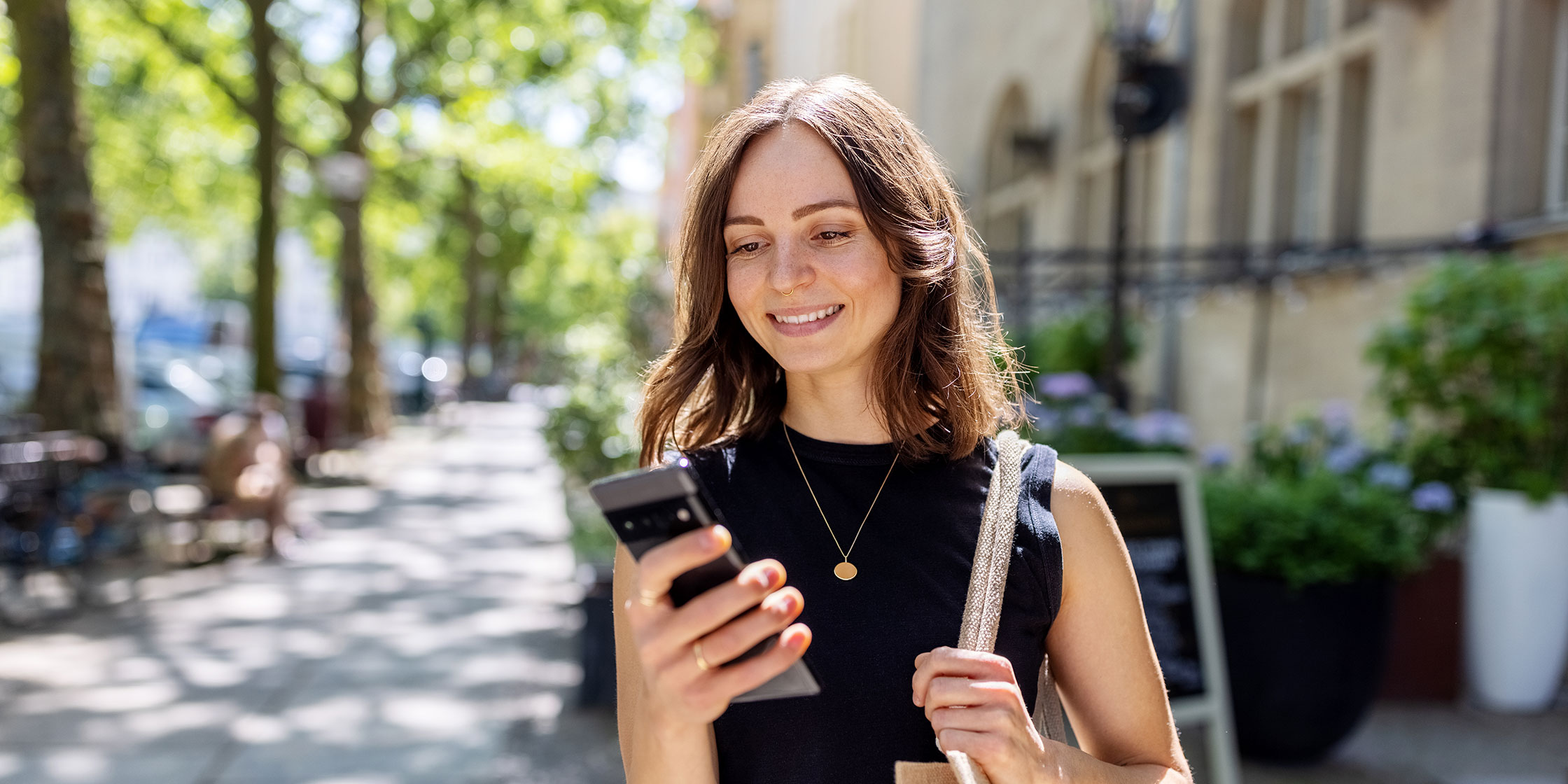 A person smiling as they use their phone to check their Capital One credit card balance.