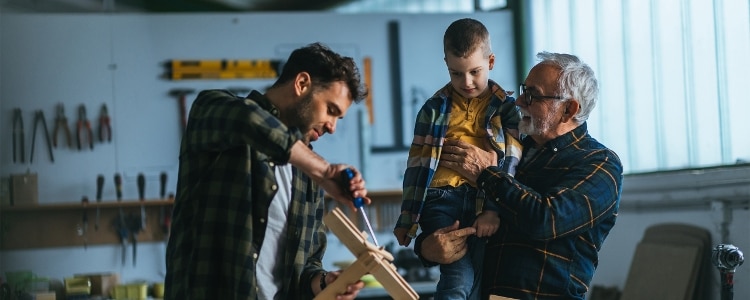 A man shows his son how to use a tool.