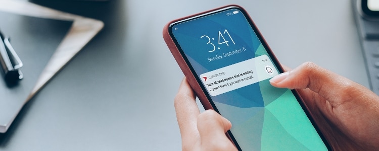 Hands holding mobile phone with Eno notification and desk in background.
