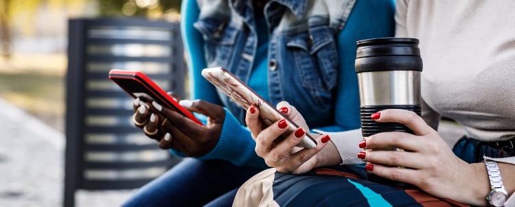 Two people sitting next to each other on their smartphones.