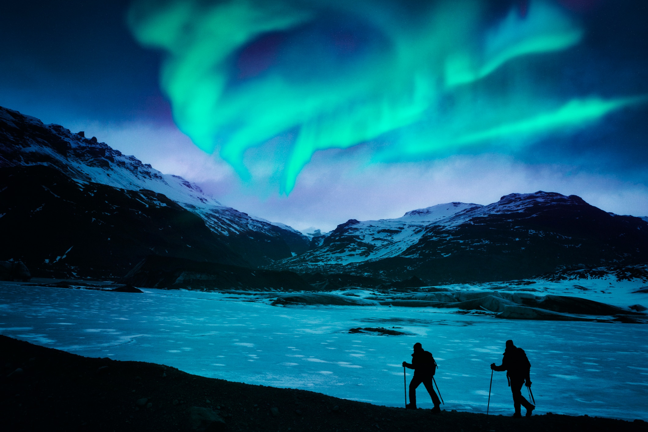 The northern lights with two hikers in the foreground.