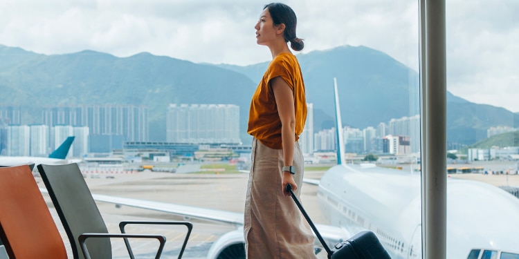 A woman walks through an airport with her luggage.