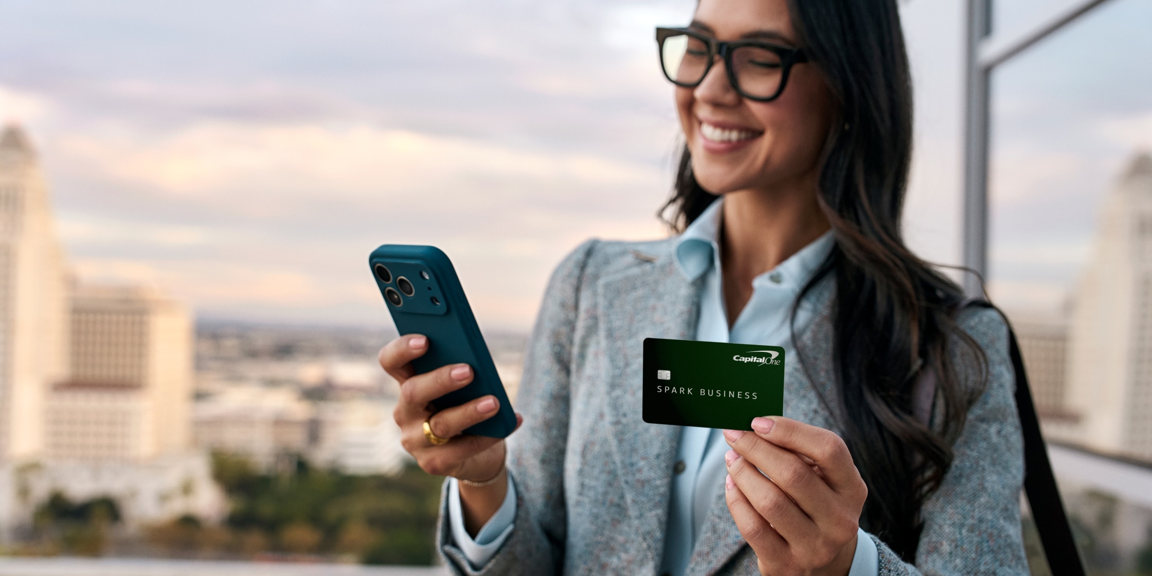 Business owner holding a Spark Cash Plus card while on her mobile phone.