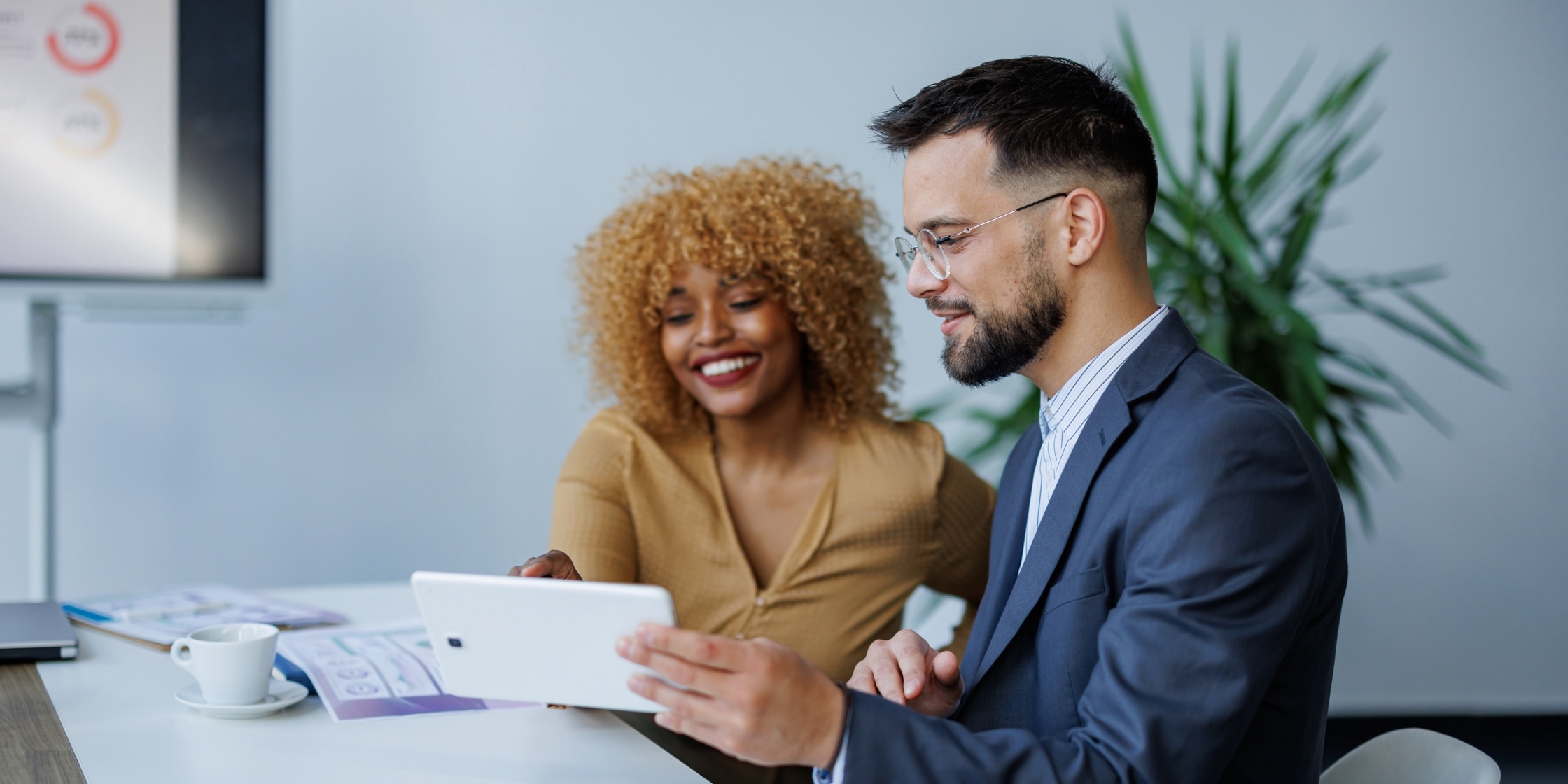 Two professionals working on a tablet, illustrating a business owner and an account manager collaborating.
