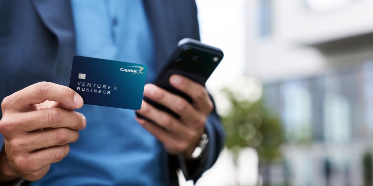 Business owner holding a Capital One Venture X Business card.