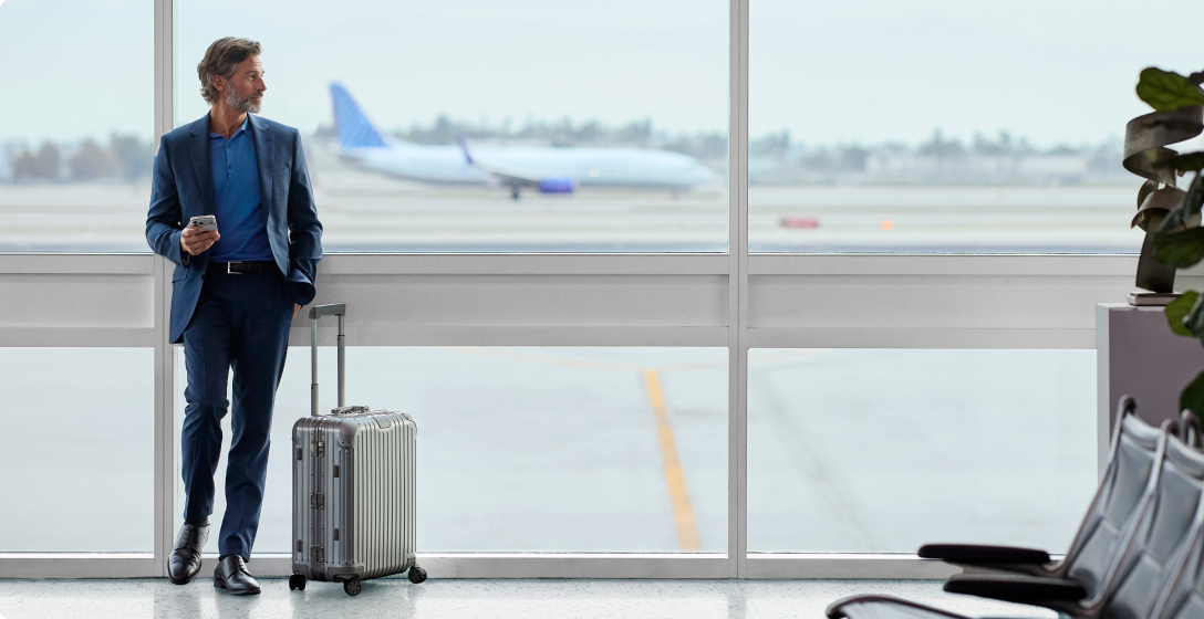 Business owner dressed in a suit waiting for a flight in an airplane terminal.