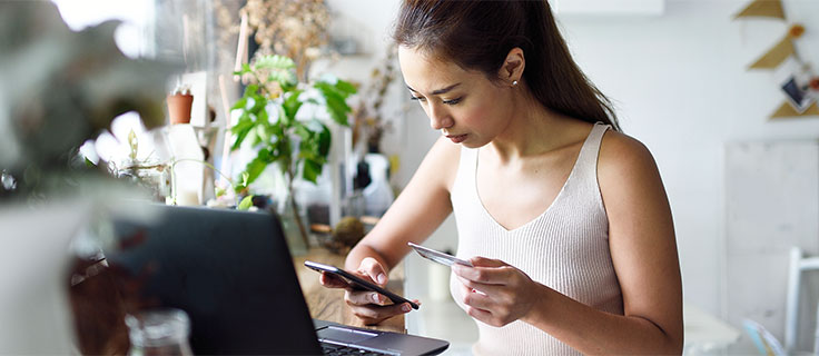 Woman sitting at desk looking at a phone.