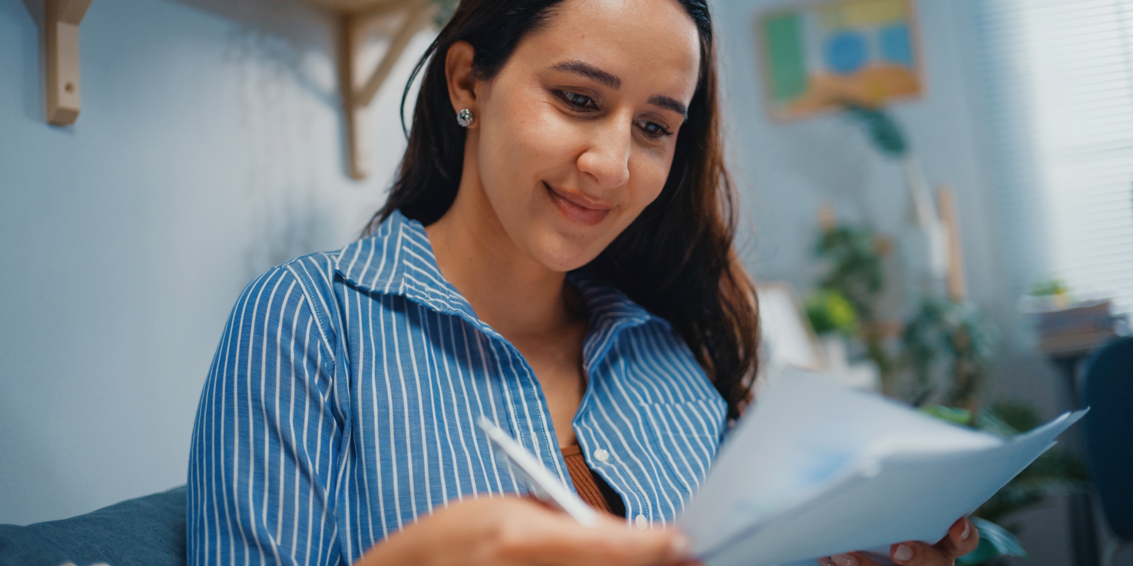 A woman in a striped blue button-down shirt looks over papers.