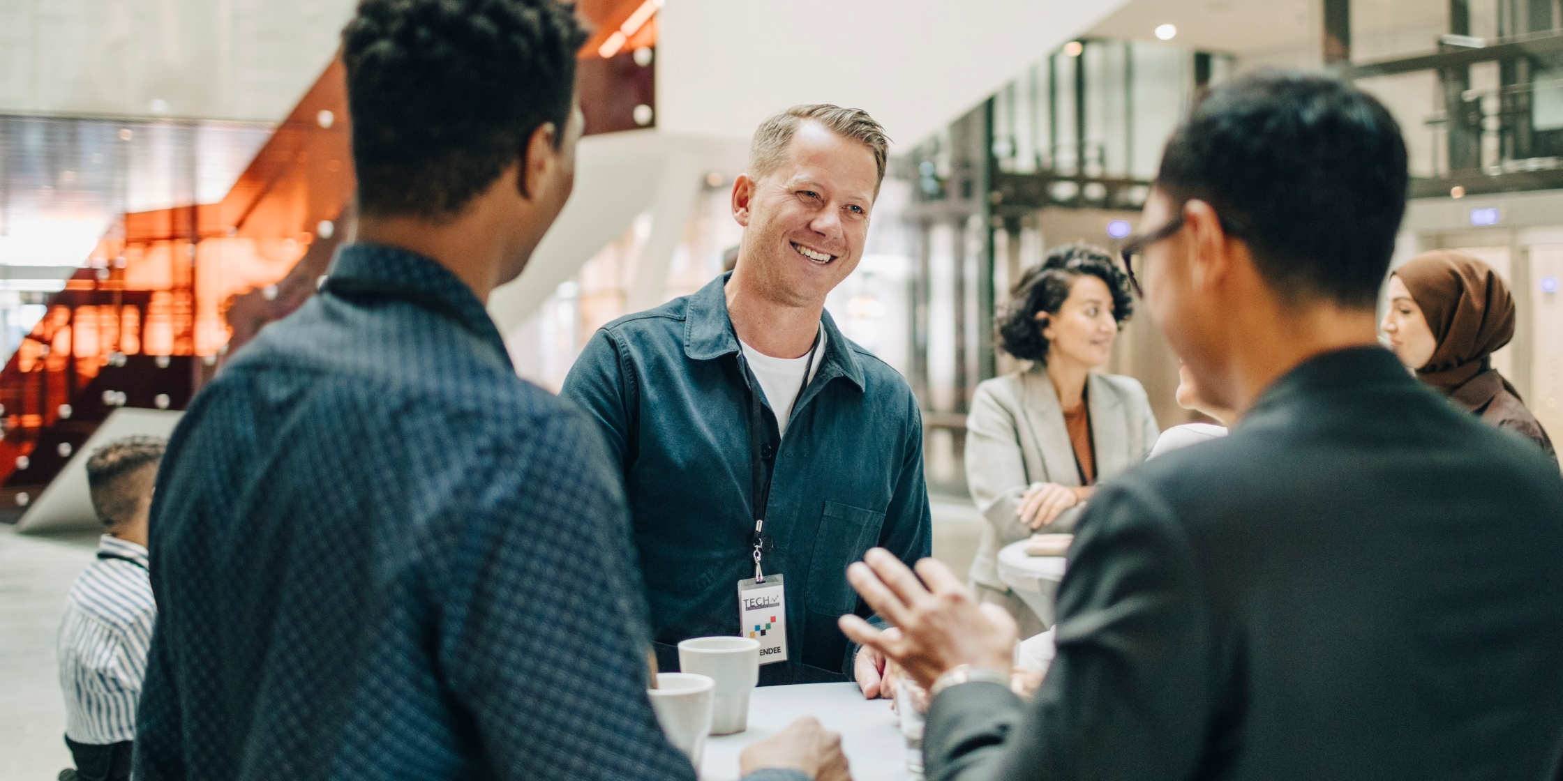 Colleagues talk together while standing around a table in an office.