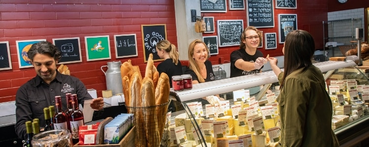 Employees interact with a customer across the counter at Antonelli's Cheese Shop, a husband-and-wife-owned cheese shop in Austin, Texas.