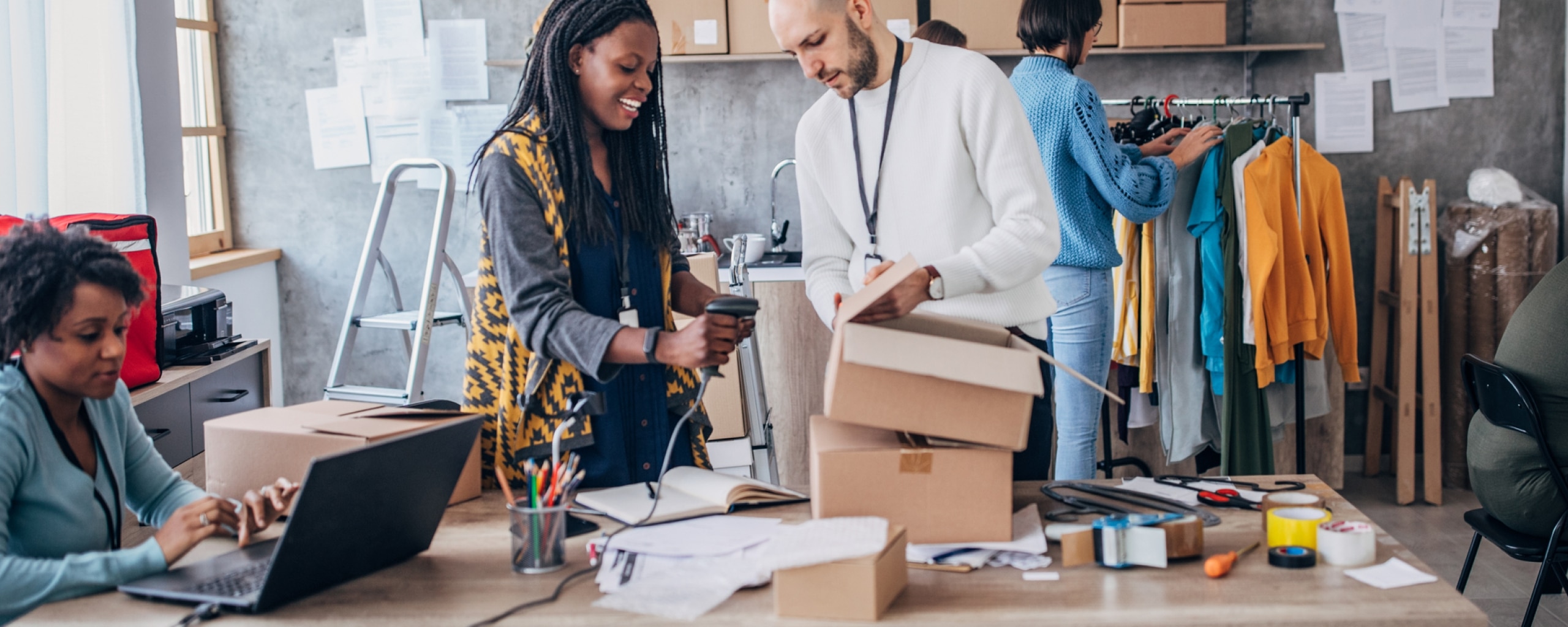 A group of people work to ship inventory in a busy office.