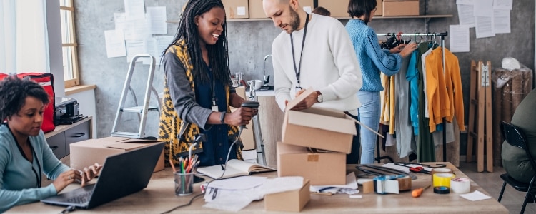 A group of people work to ship inventory in a busy office.