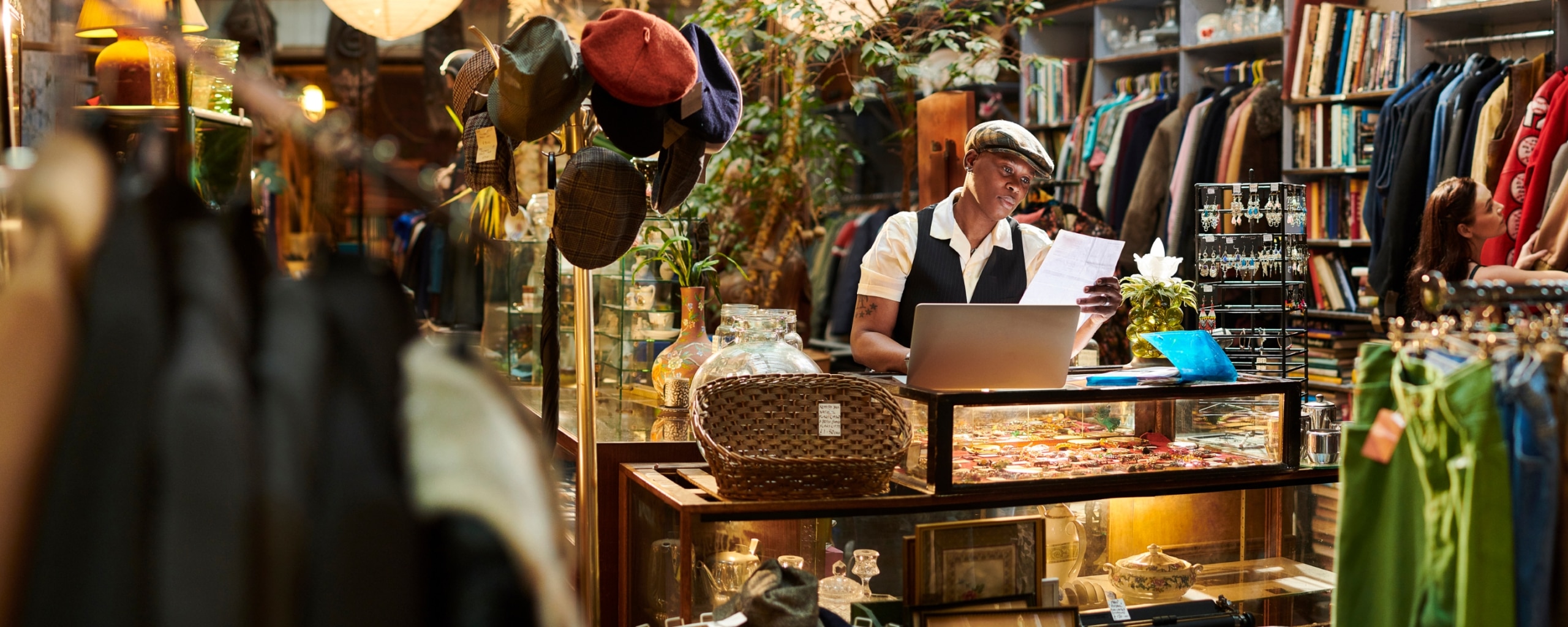 A business owner stands behind their business' counter looking over invoices.