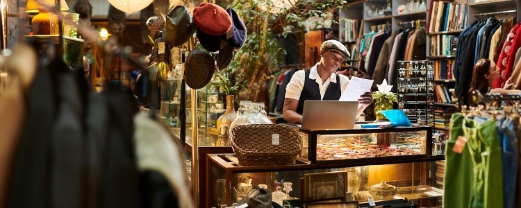 A business owner stands behind their business' counter looking over invoices.