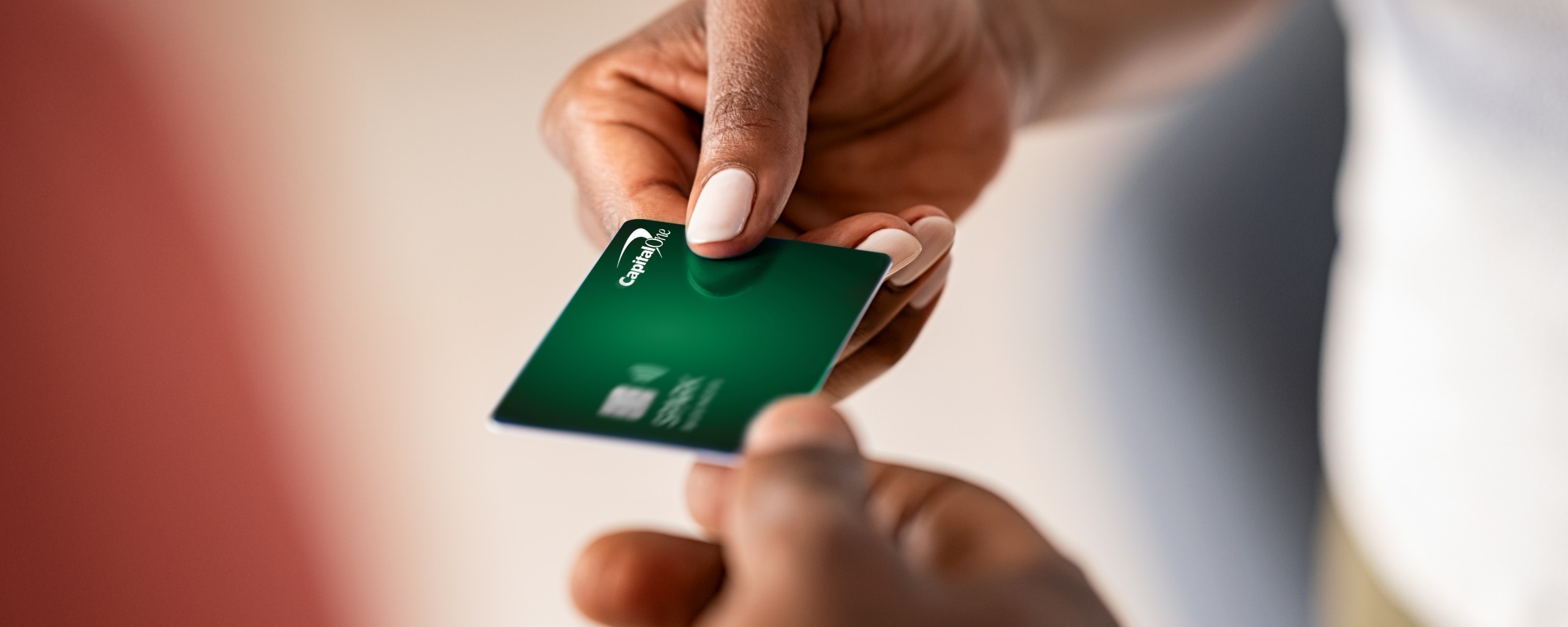 Close up of Capital One credit card exchanging hands.