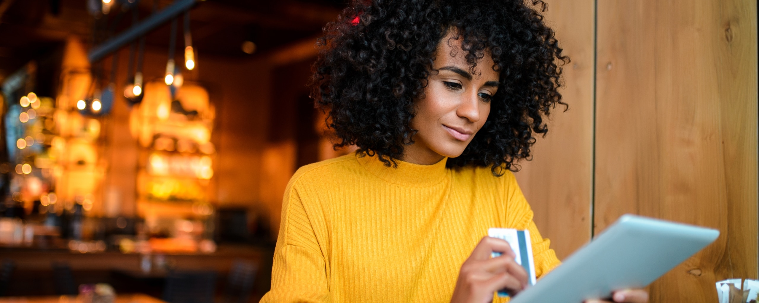 Person holding a credit card in one hand and a tablet in the other.