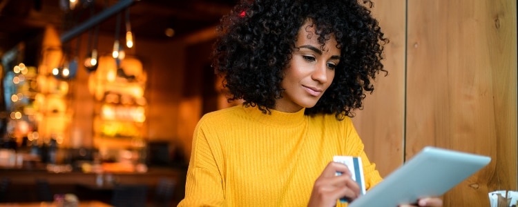 Person holding a credit card in one hand and a tablet in the other.