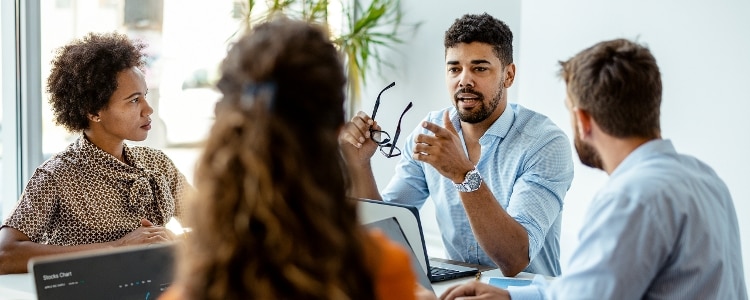 Group of employee sitting around a table in the office while having a conversation.