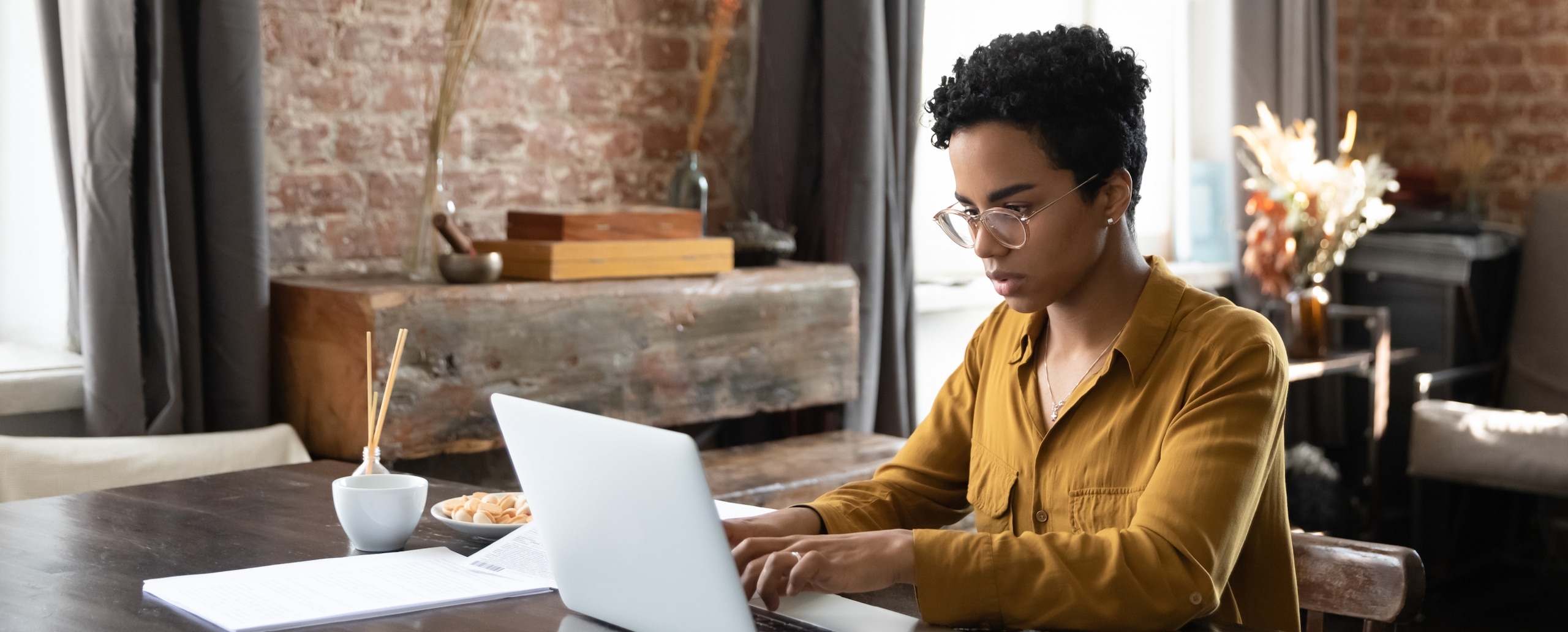 Woman working on a laptop at a table in her home.