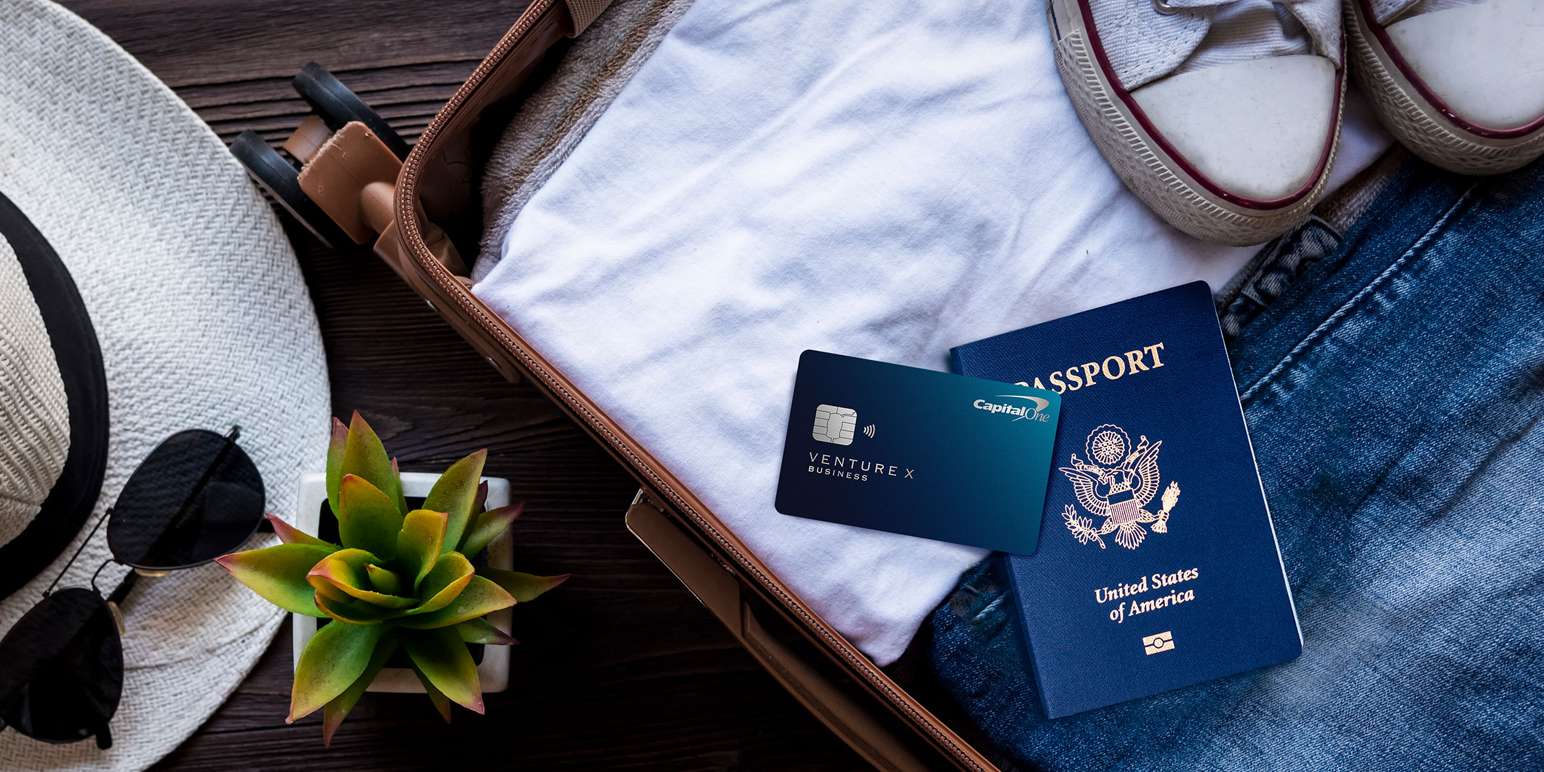 A Venture X Business card and a passport sit atop luggage.