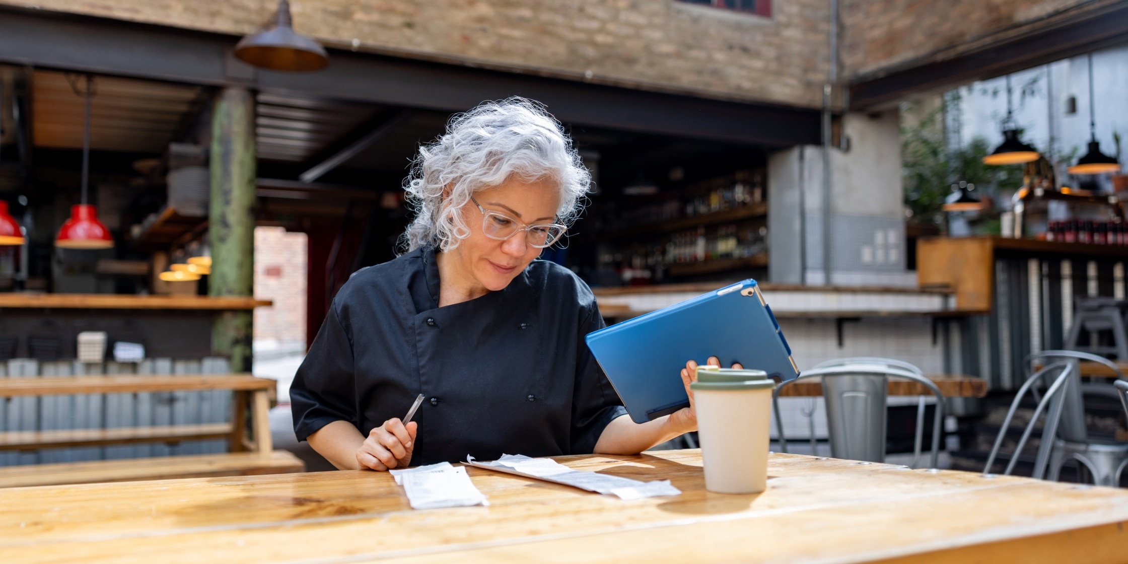 A restaurant chef looking at the books, managing business finances to reduce financial stress.