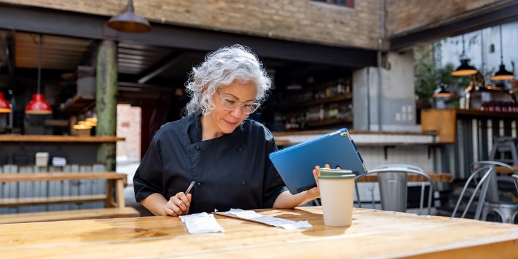 A restaurant chef looking at the books, managing business finances to reduce financial stress.