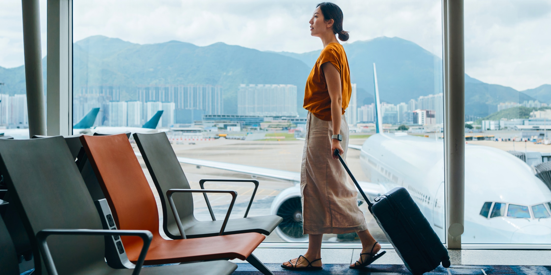 A woman walks through an airport with her luggage.